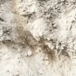 Poröse sandfarbene Erdschicht mit ockerfarbenen Steinchen und Rissen