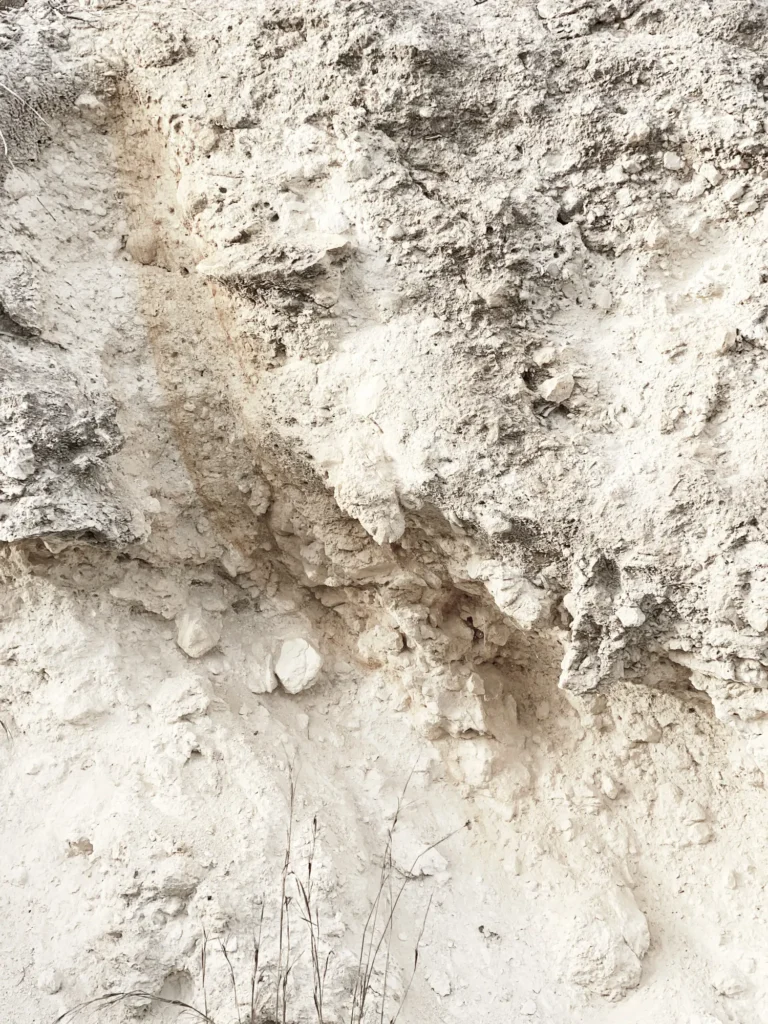 Poröse sandfarbene Erdschicht mit ockerfarbenen Steinchen und Rissen