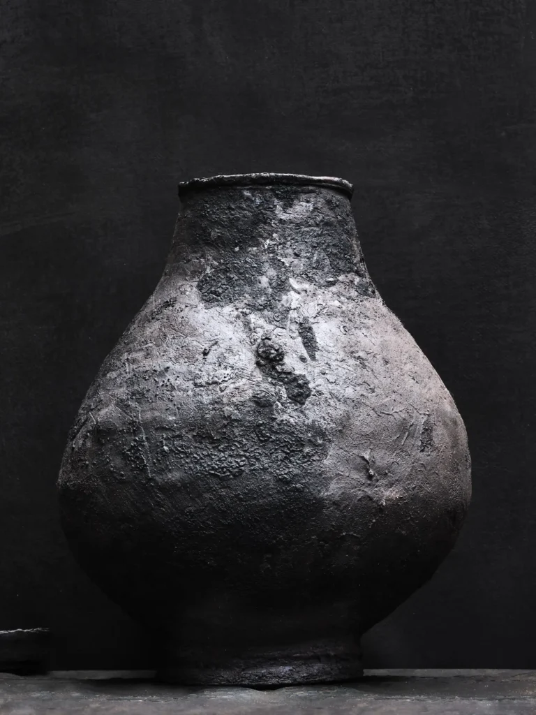 Große, kegelförmige Stoneware-Vase in schwazer Lava-Optik, aufgenommen vor schwarz-grauem Hintergrund