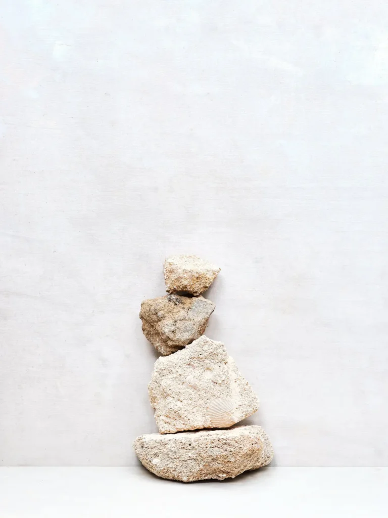 Gestapeltes Arrangement von erdfarbenen Tuff-Stones vor hellem Hintergrund