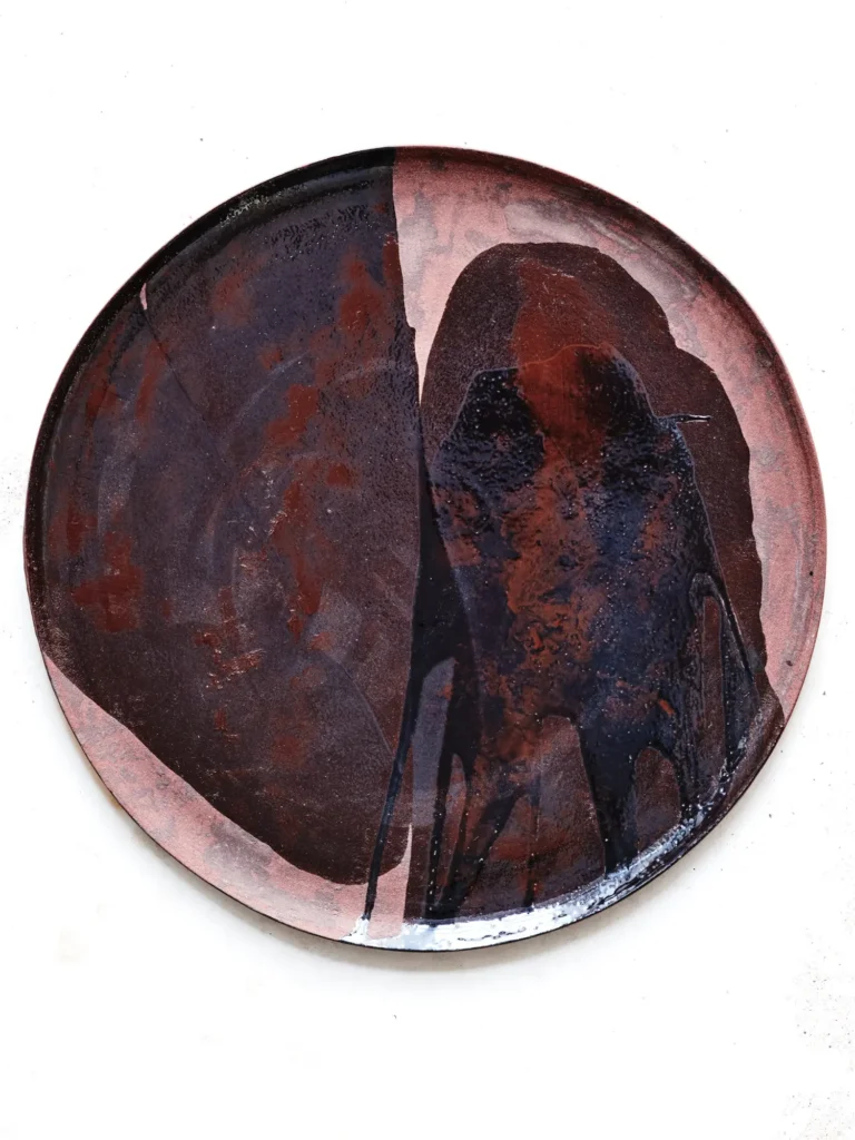 Rotlich-patinierter Stoneware-Teller, aufgenommen von Dietlind Wolf vor hellem Hintergrund
