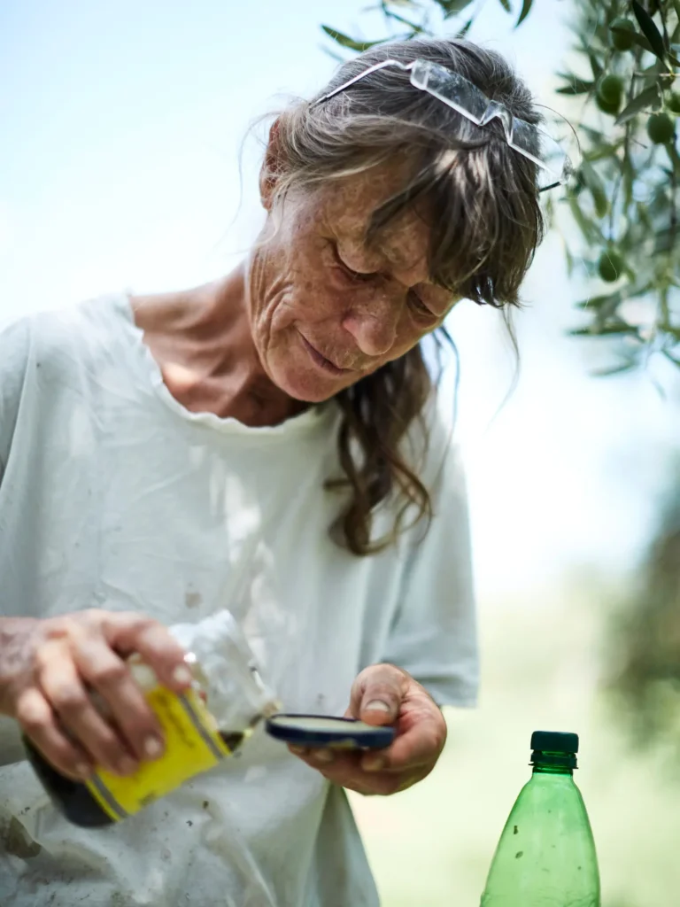 Frau misst Flüssigkeit aus einer Flasche im Garten ab.
