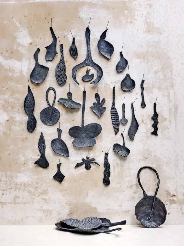 An der Wand hängende, schwarze Keramikformen in organischen Silhouetten